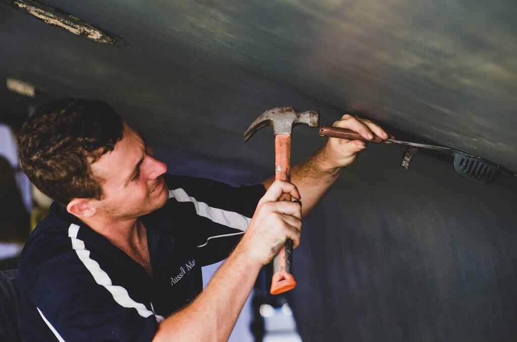 Trades person repairing hull of boat
